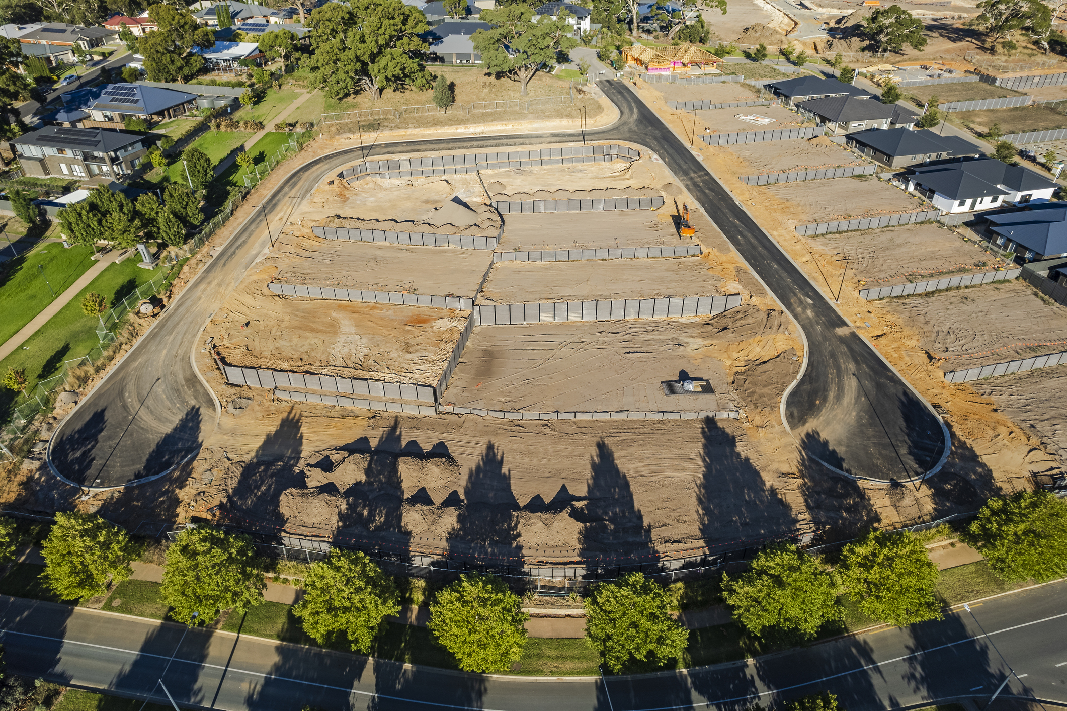 Aerial View New Rural Housing Development Earthworks, Retaining Walls, Access Roads With Display Homes And Late Afternoon Shadows
