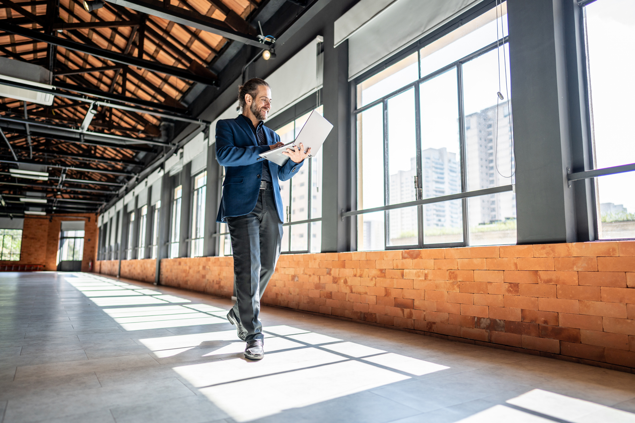 Mature Businessman Walking And Using Laptop At Empty Office For Sell At Real Estate