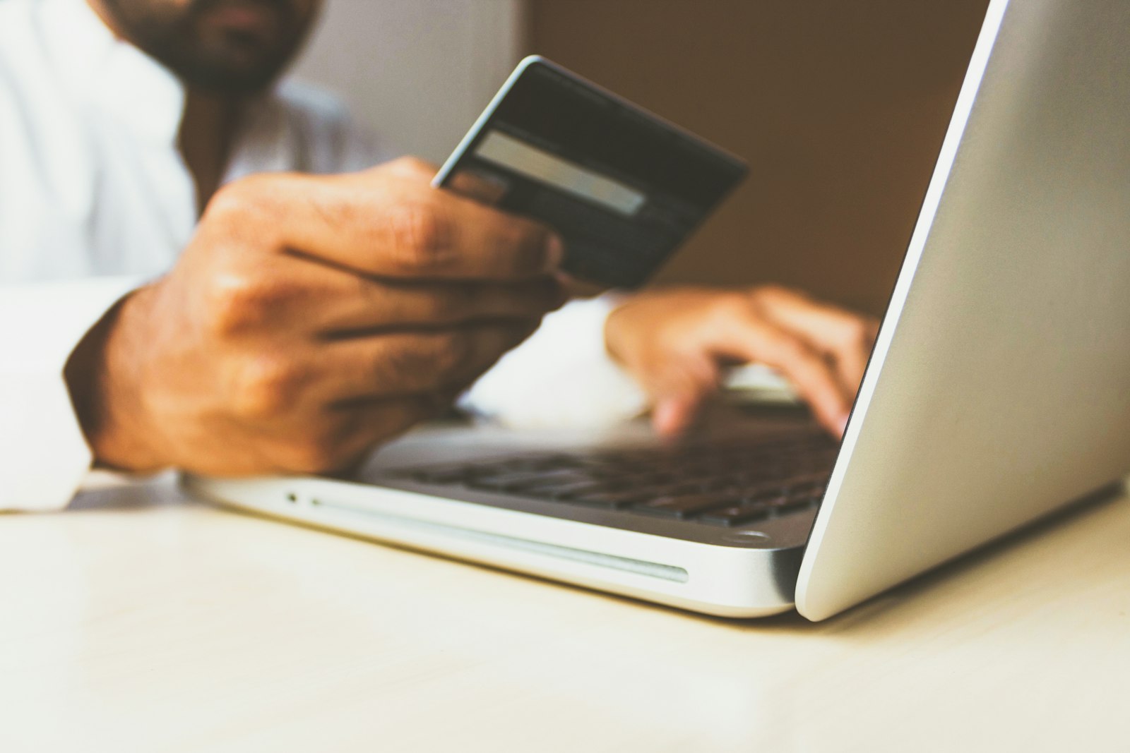 Paying a property deposit by bank transfer Person holding a bank card while making an online payment on a laptop